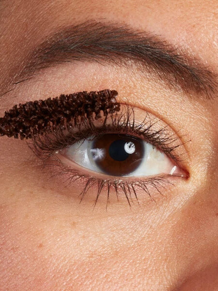 Close up of a model applying mascara on their eye.