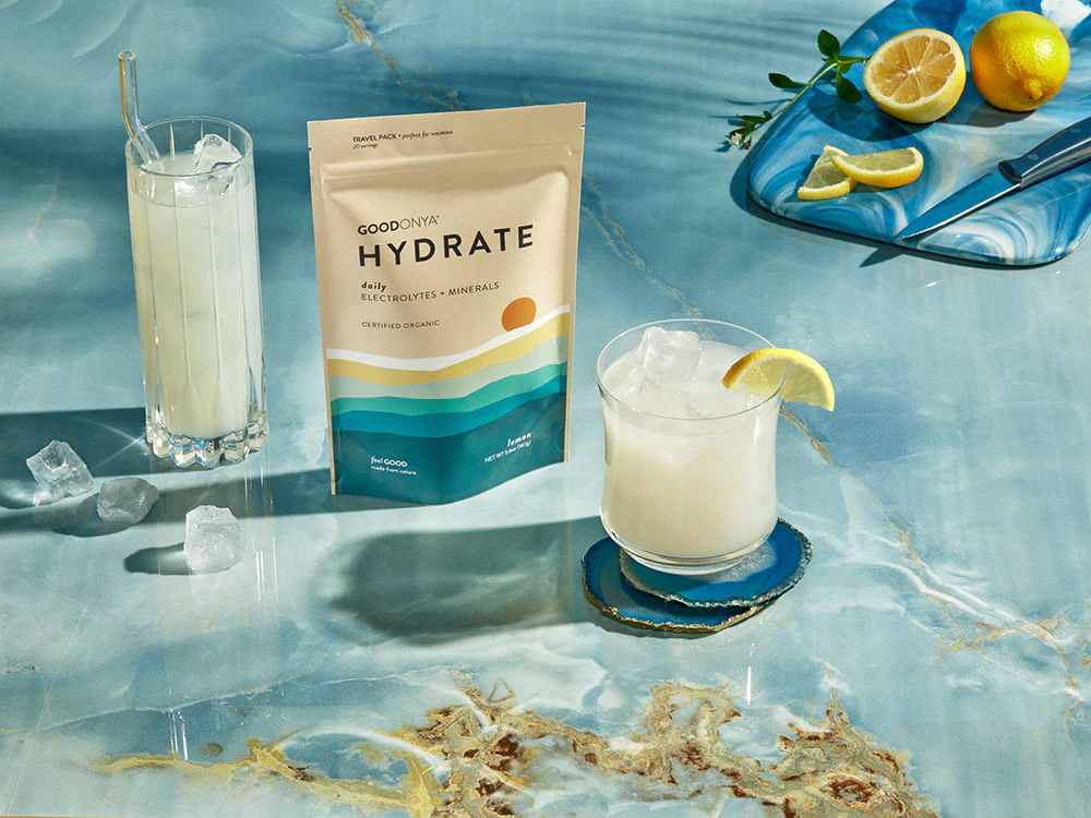 A bag of the product next to a glass with a lemon slice in it.