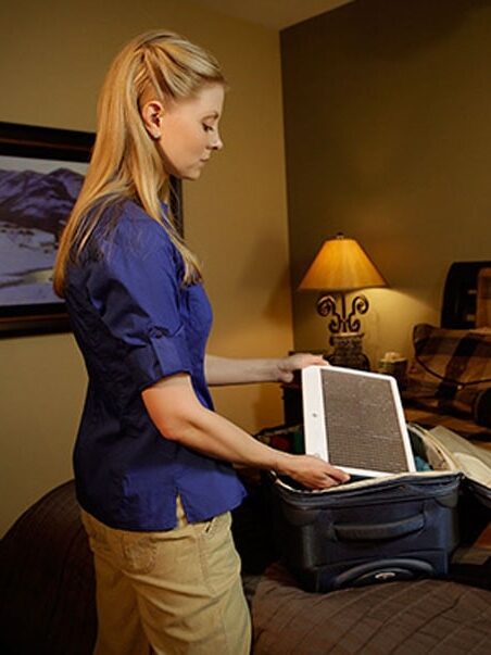 A model placing an Alaska Northern Lights lamp in their suitcase.