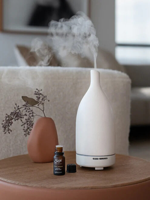 A white Saje diffuser, with a Saje essential oil next to it.