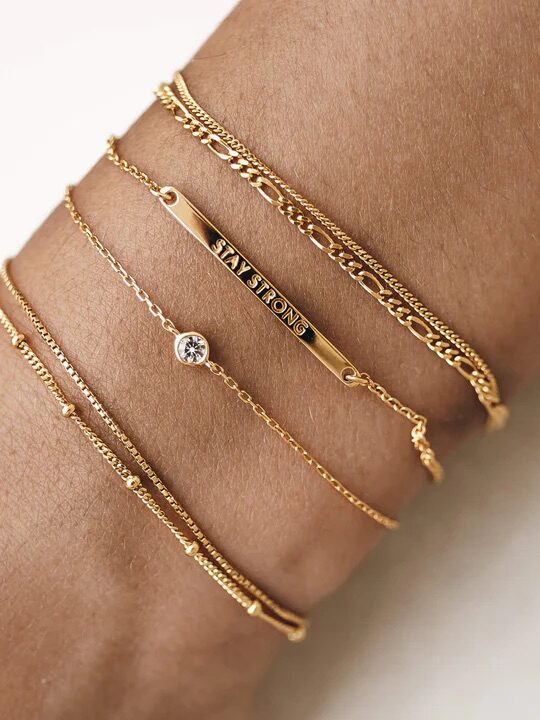 A variety of thin gold bracelets from Linjer on a model's wrist.