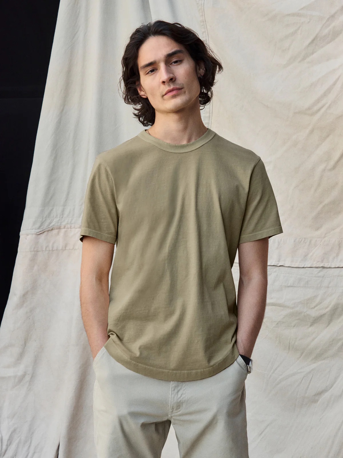 A model wearing a moss green tee from Buck Mason. 