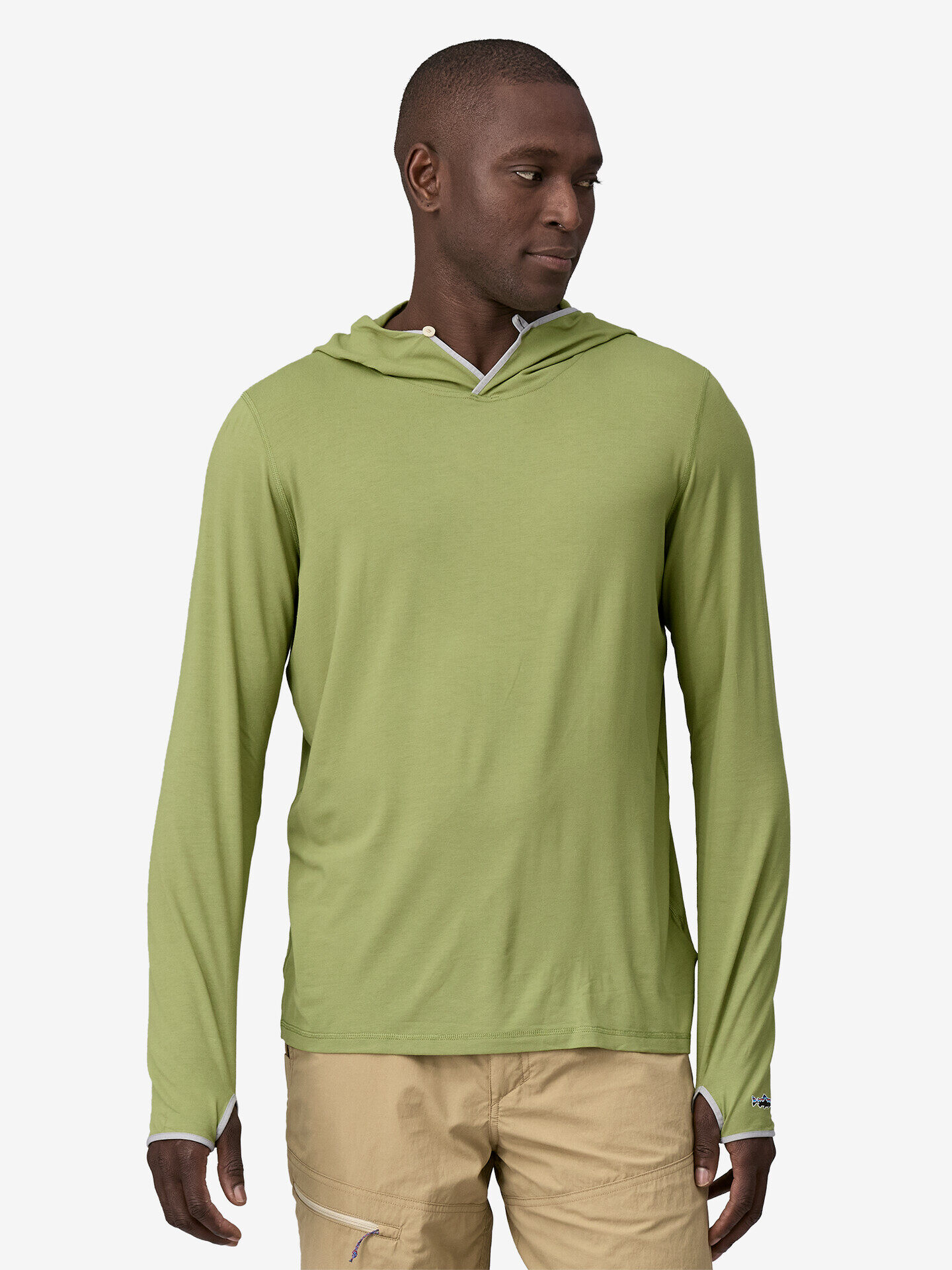 A man is wearing a light green long-sleeve hoodie and beige pants, standing against a plain white background.