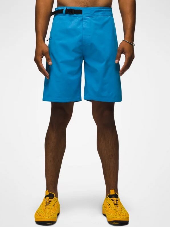 Person wearing blue athletic shorts, a black belt, and yellow woven sneakers stands against a plain white background.