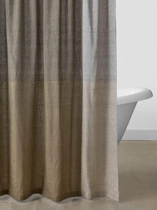 A neutral-toned shower curtain with a gradient design hangs in front of a white bathtub in a minimalistic bathroom setting.