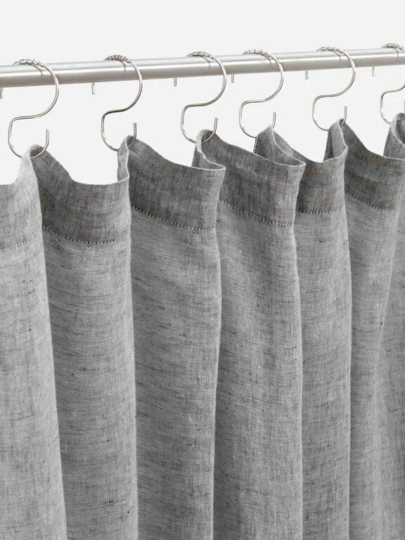 A set of grey fabric curtains hanging from a metal rod with metal rings/hooks.