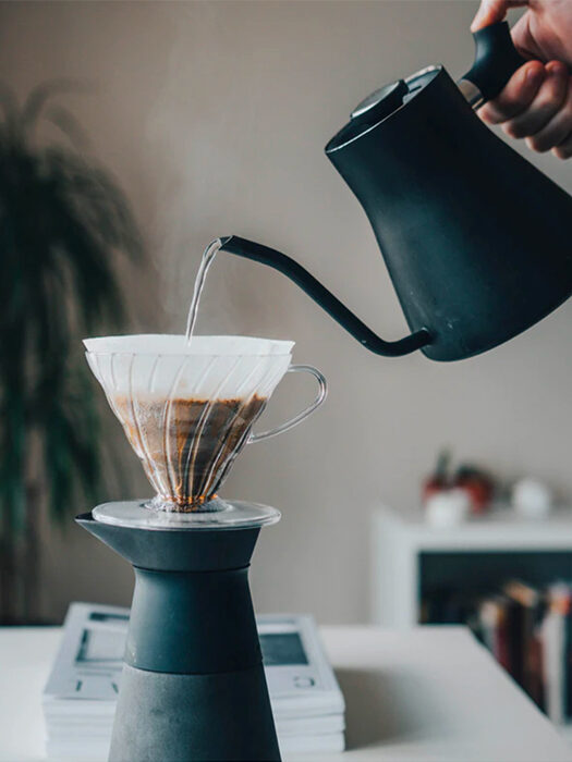 A kettle of water being poured into a pour-over coffee maker.