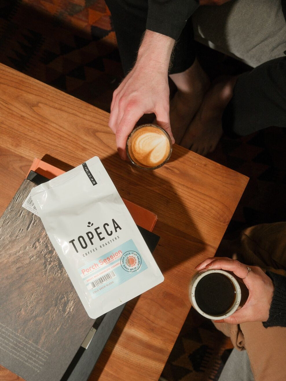 A latte and a cup of coffee next to a bag of Mistobox coffee.