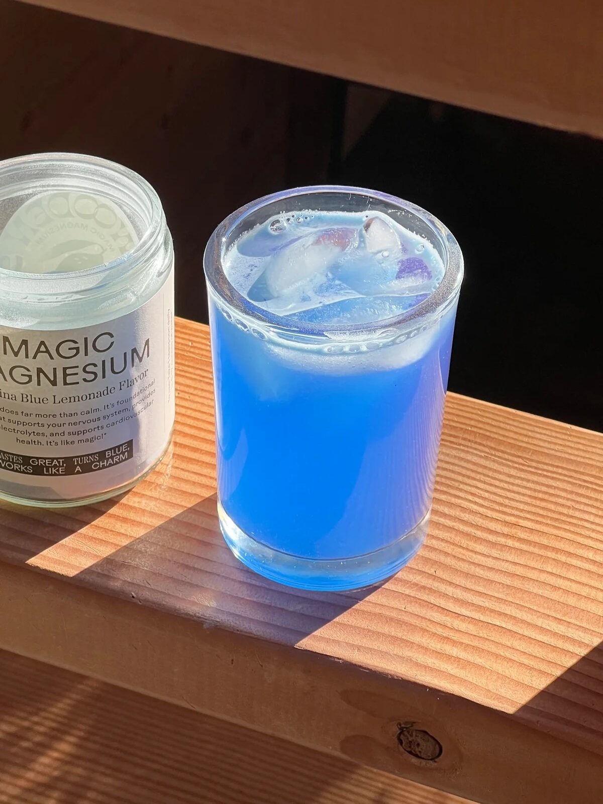 A jar of Magic Magnesium next to a cup filled with the prepared magnesium drink.