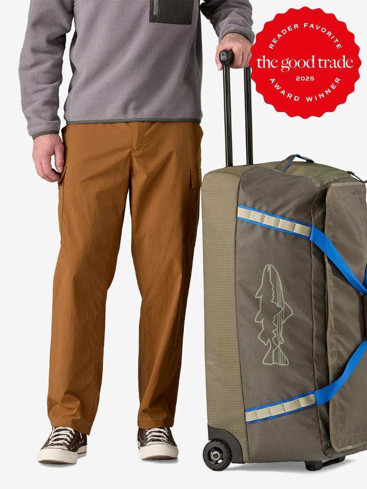 Person standing beside a green wheeled duffel bag with a fish outline design. Red "Reader Favorite" award badge for The Good Trade 2025 is displayed above.