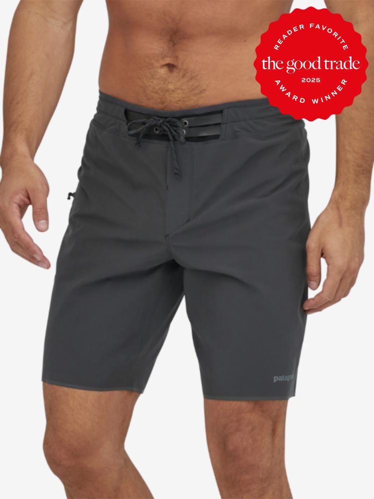 Man wearing dark gray swim trunks with a drawstring and pocket. A red badge reads "Reader Favorite: The Good Trade Award Winner 2025" in the upper right corner.