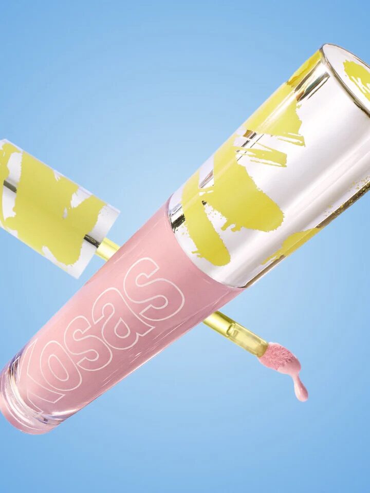 A pink lip gloss tube with a yellow design on the cap, angled against a blue background, with an open applicator showing product.