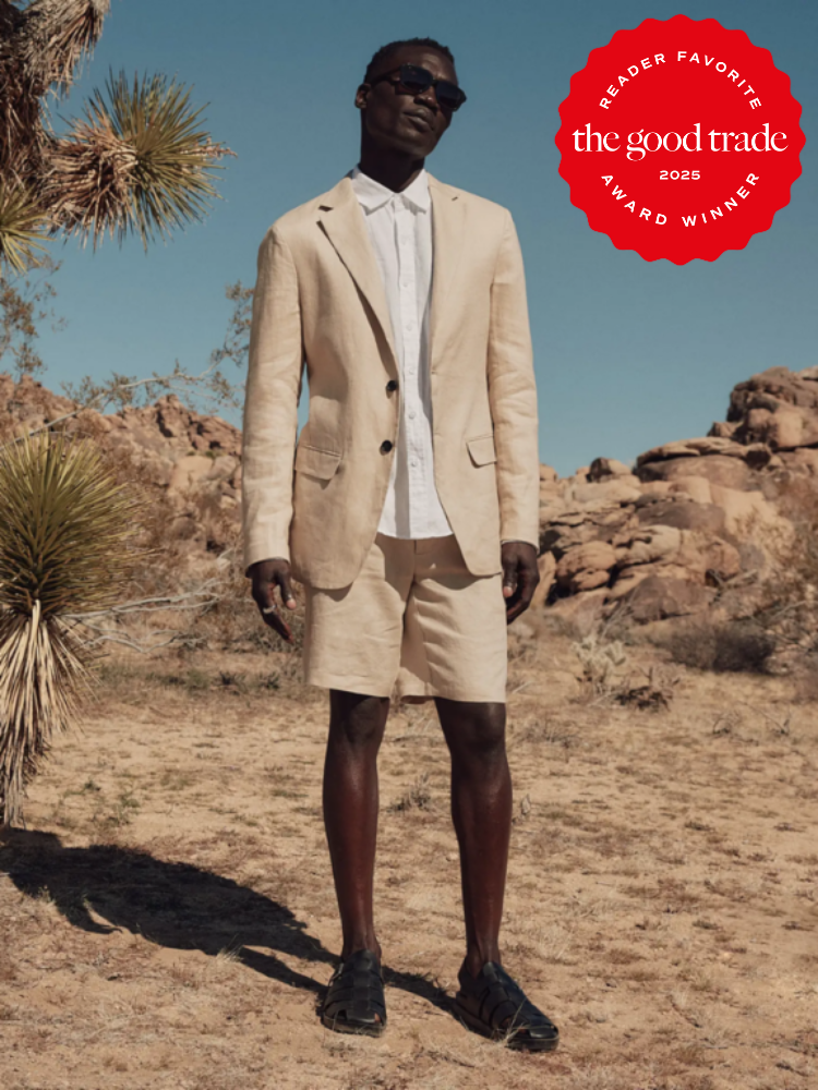Person in a beige suit and shorts stands in a desert landscape. They wear sunglasses and dark shoes. An award badge reads: "Reader Favorite, the good trade, 2025 Award Winner.