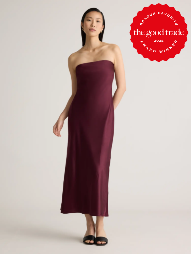 Woman in a strapless burgundy dress and black sandals stands against a plain background. A red badge reading “The Good Trade Reader Favorite Award Winner 2025” is on the top right.