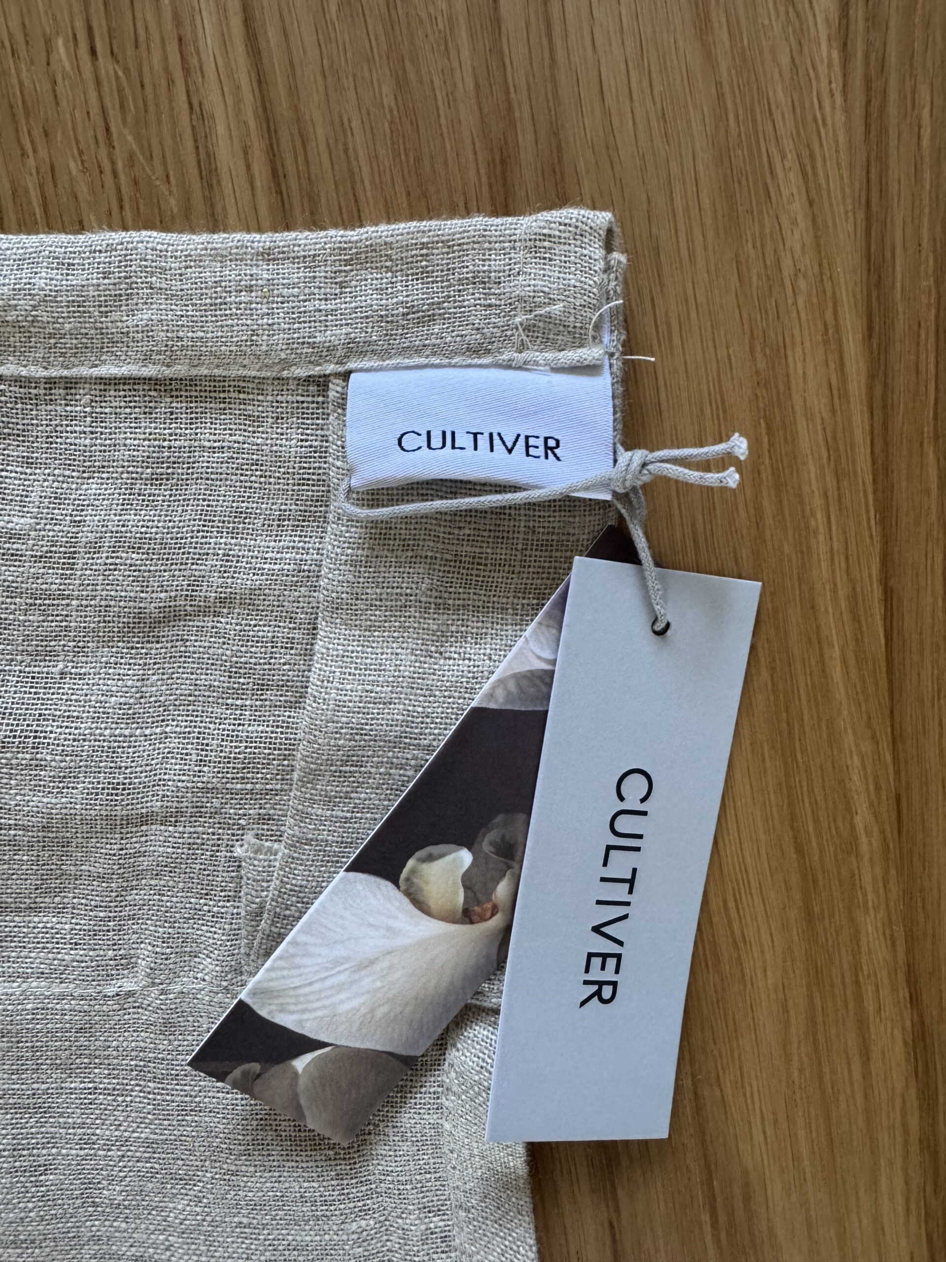 Linen fabric with a "Cultiver" tag and label on a wooden surface.