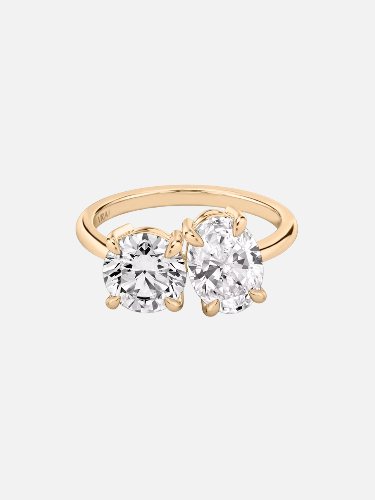 Gold ring with two large adjacent gemstones, one round and one oval.