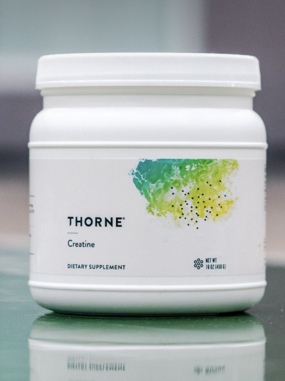 A white container of Thorne creatine dietary supplement with a colorful abstract label.