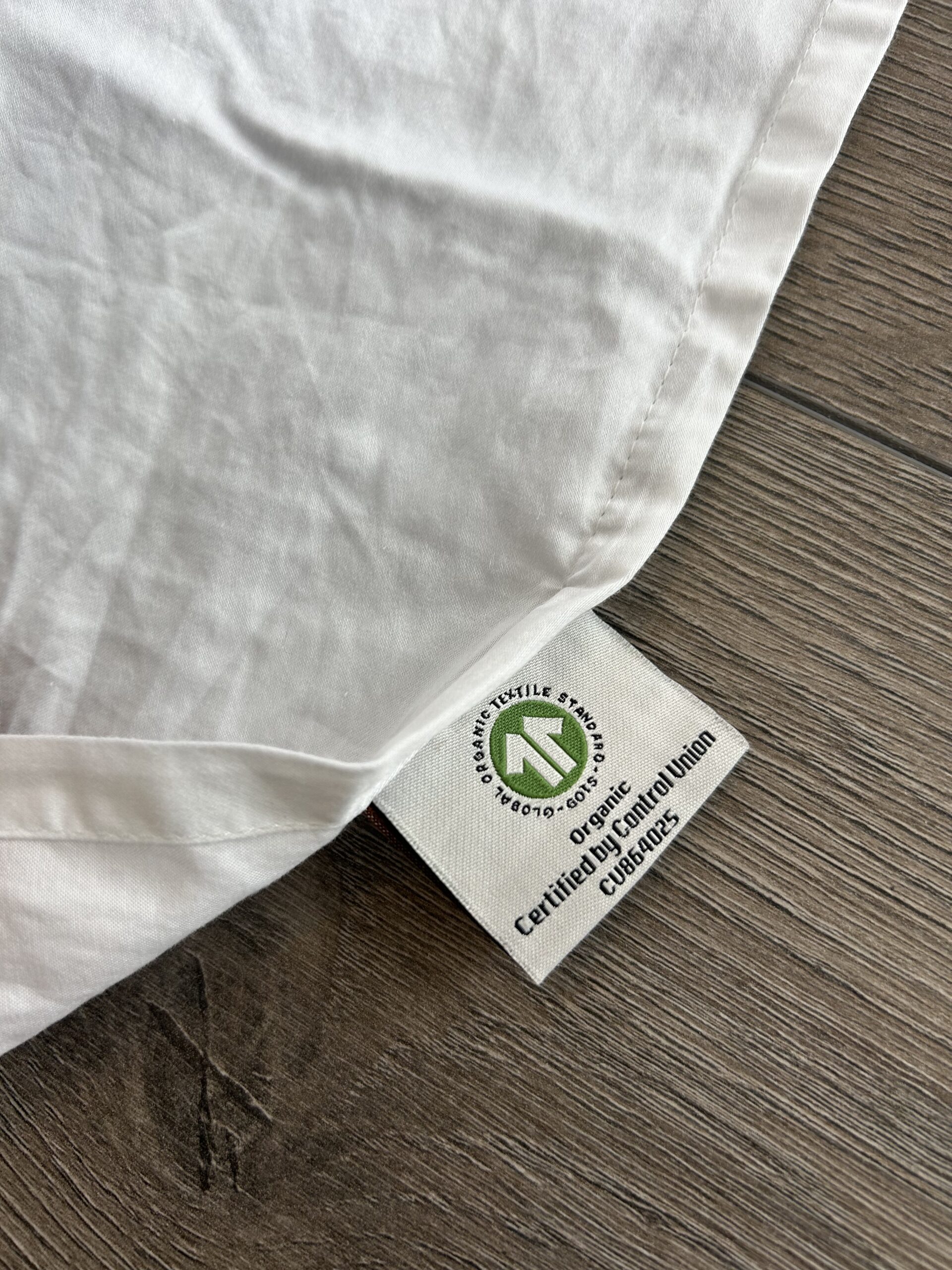 A white fabric with a GOTS certified organic label lies on a wooden surface.