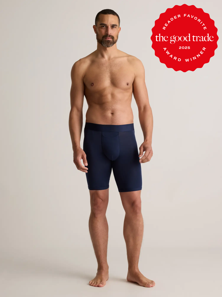 A shirtless man stands facing forward wearing navy blue boxer briefs. A red badge in the upper right corner reads "The Good Trade 2025 Award Winner.