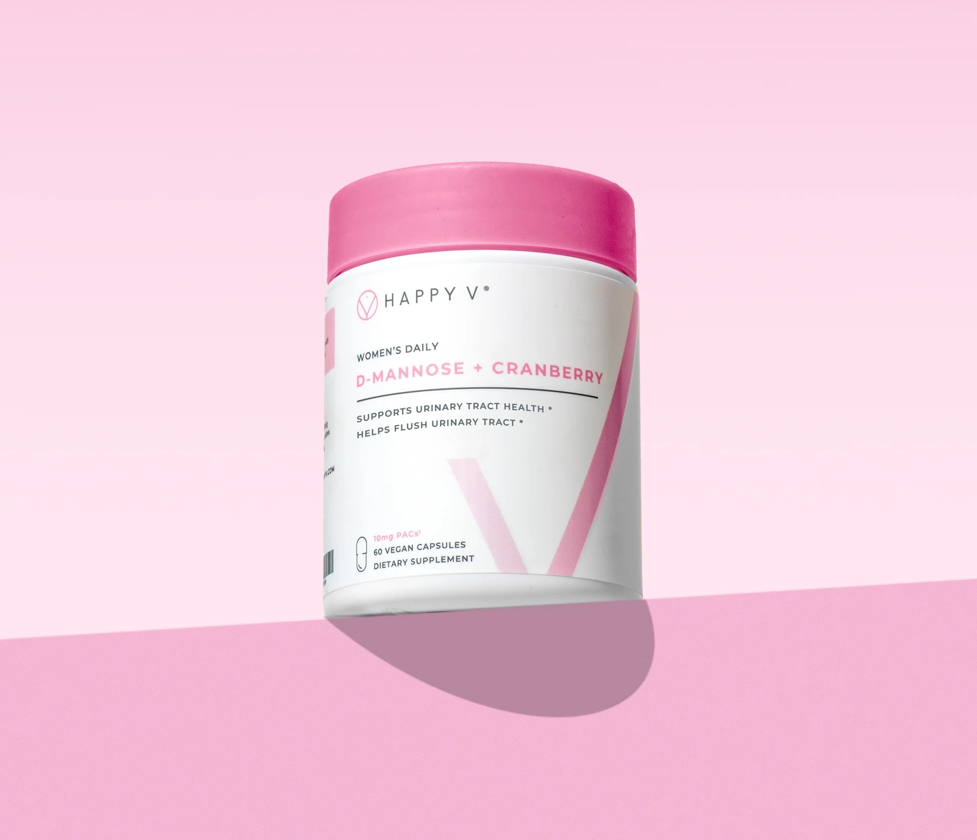 A container of Happy V D-Mannose + Cranberry dietary supplement capsules for women's urinary tract health, against a pink background.