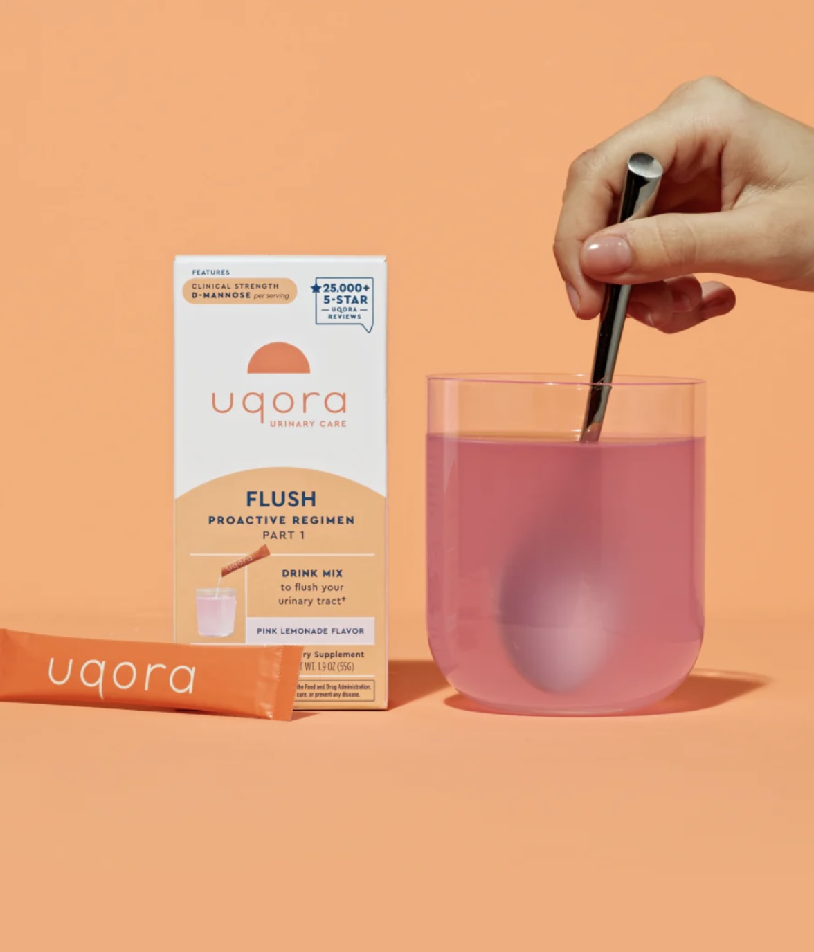 A hand stirs a glass of pink drink with a metal straw next to a box and packet labeled "Uqora Flush Proactive Regimen Part 1" on a peach-colored background.