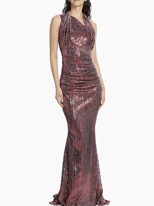 A woman wearing a sleeveless, floor-length, form-fitting pink sequin gown with a draped neckline.