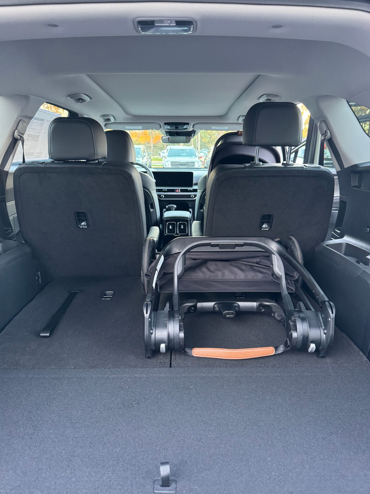 Photo of an SUV interior with rear seats partially folded down and a stroller with a tan handle placed in the cargo area.